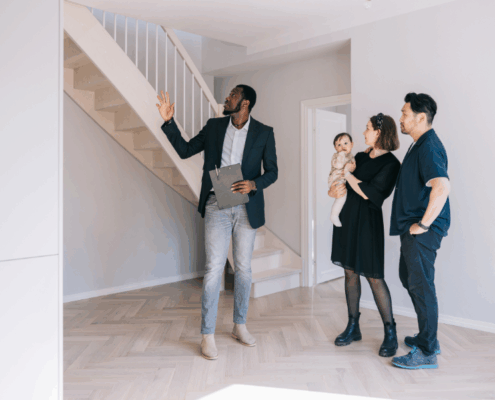 Real estate agent showing a home to a young couple with a baby, discussing mortgage options