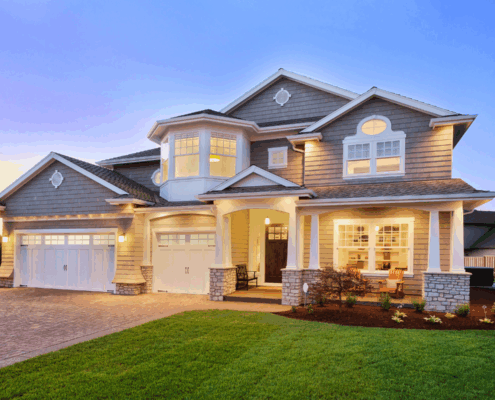 Modern two-story suburban home with warm exterior lighting at sunset, representing the dream of homeownership.