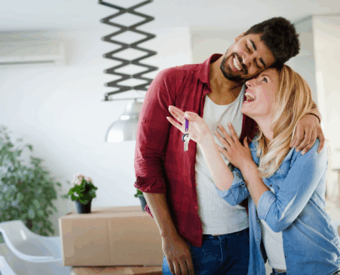 Young couple unpacking boxes in their new home, symbolizing a hopeful start to homeownership.